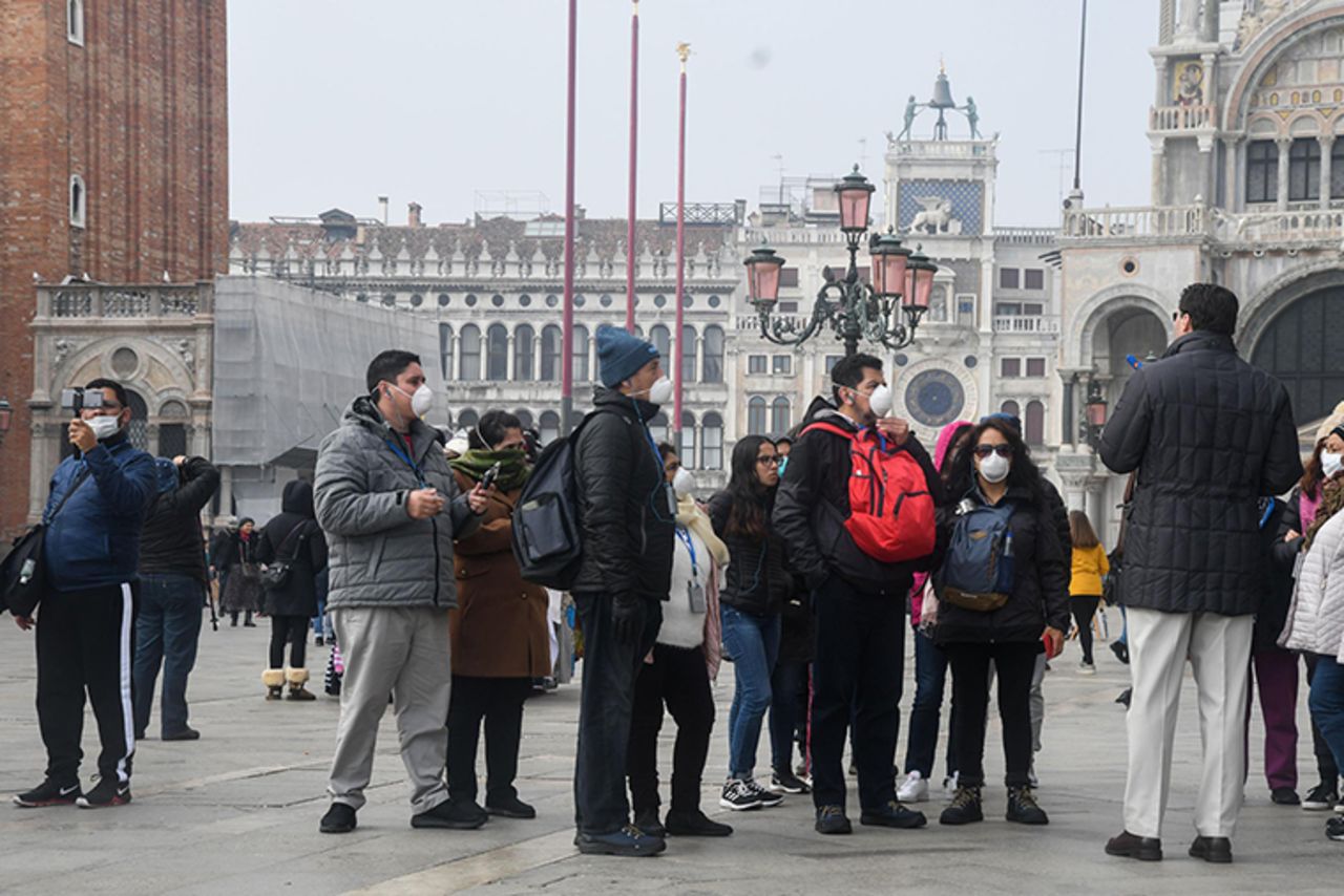 Tourists wearing protective masks visit Venice on February 25, during the usual period of the Carnival festivities which have been cancelled following an outbreak of the  novel coronavirus in northern Italy.