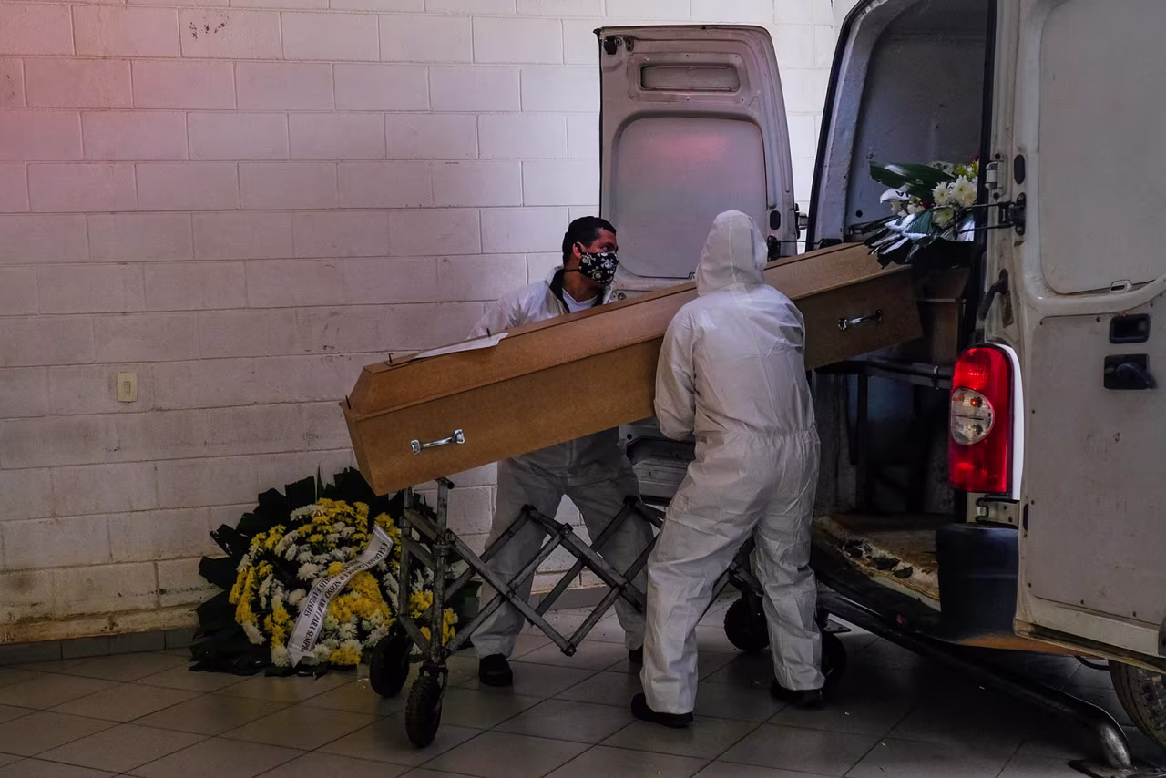Employees at the Vila Formosa cemetery unload a coffin from a van in San Paulo, Brazil, on May 23.