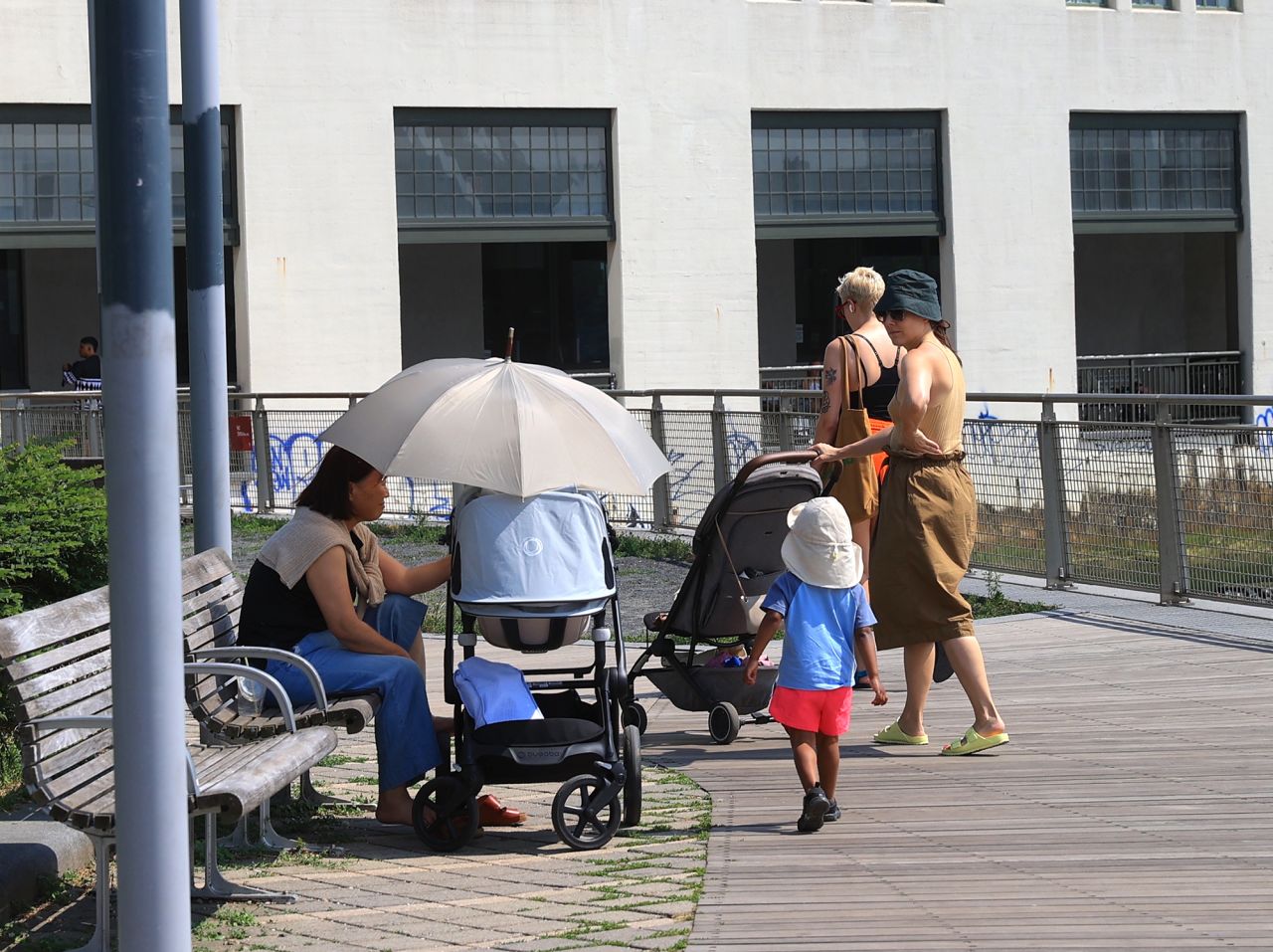 A woman puts an umbrella over a stroller to keep it cool during hot weather in New York on June 18.