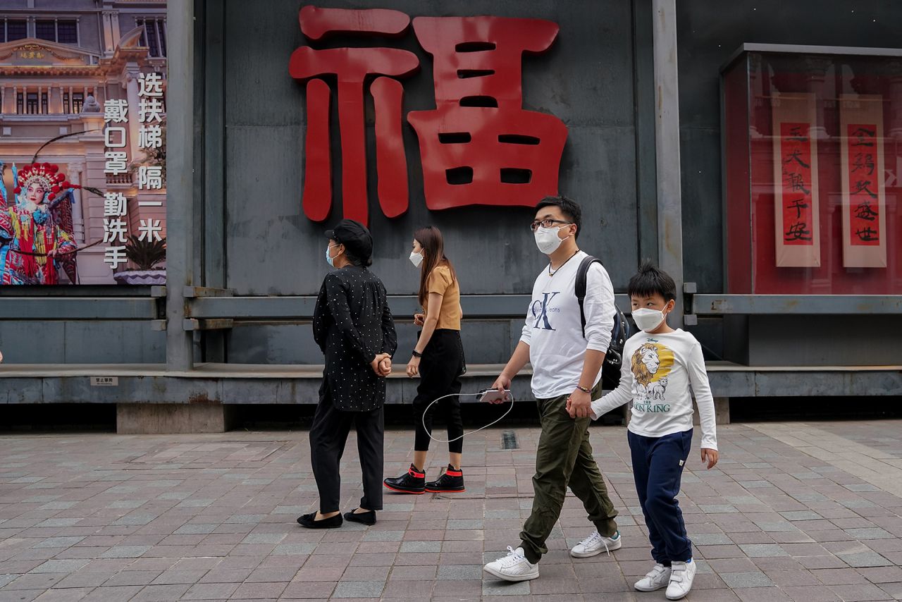 Shoppers wear protective masks as they walk on a commercial street on May 8, in Beijing.