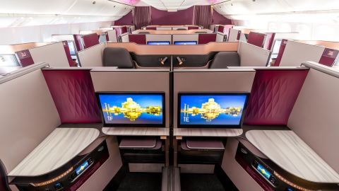 A photo of a well lit Qatar Airways Qsuites business class cabin