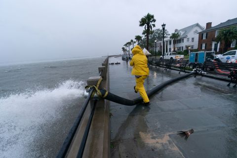 A worker steps over a pump removing water from the Battery in Charleston on Friday.