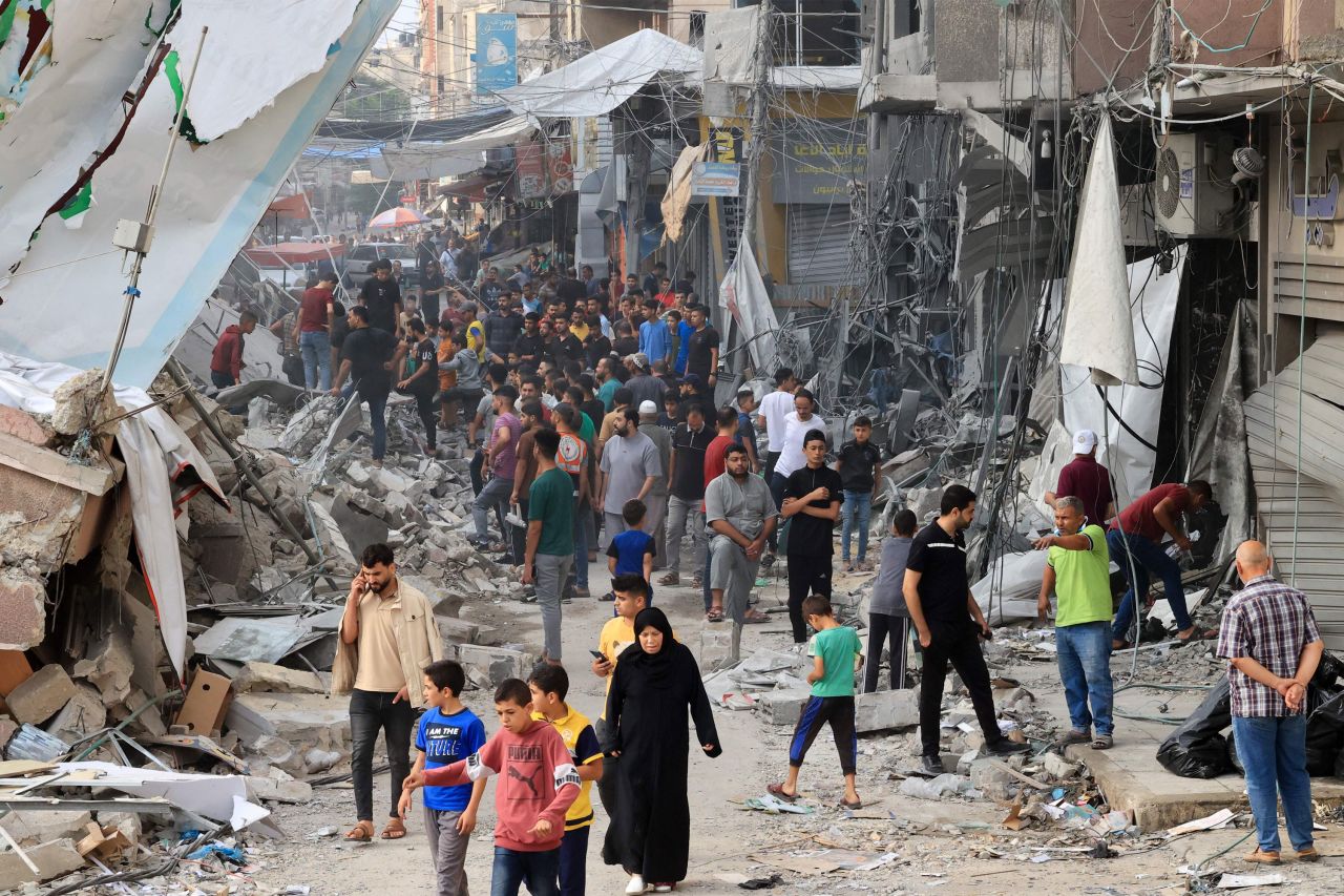 Palestinians walk amid the rubble of destroyed and damaged building in the heavily bombarded city center of Khan Younis in southern Gaza following overnight Israeli shelling, on October 10, 2023.