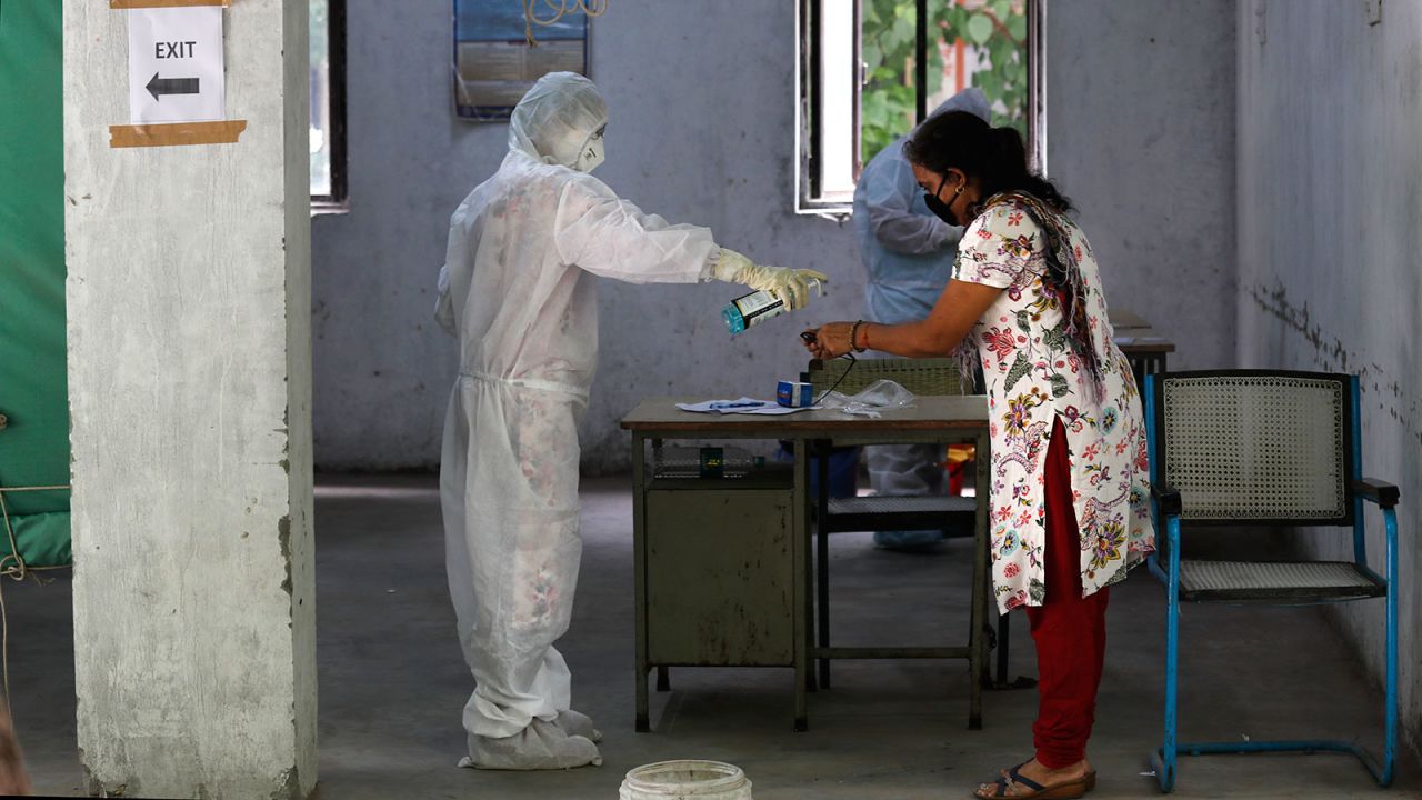 A health worker gives hand sanitizer to a woman after taking her sample for the COVID-19 rapid antigen tests in New Delhi, India on June 19.