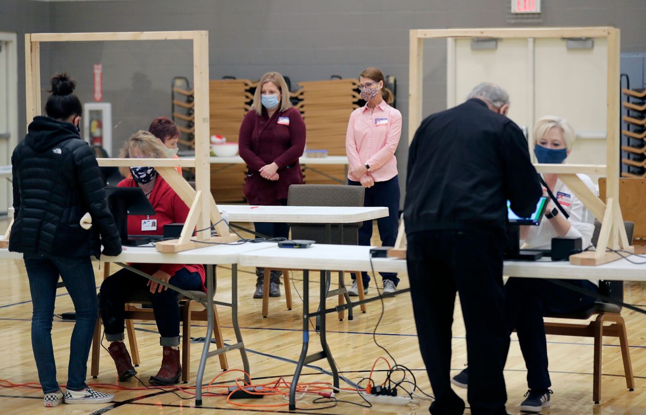 Poll observers watch as citizens receive their ballots to vote at Faith Lutheran Church Celebration Ministry Center on November 3, 2020, in Appleton, Wis.