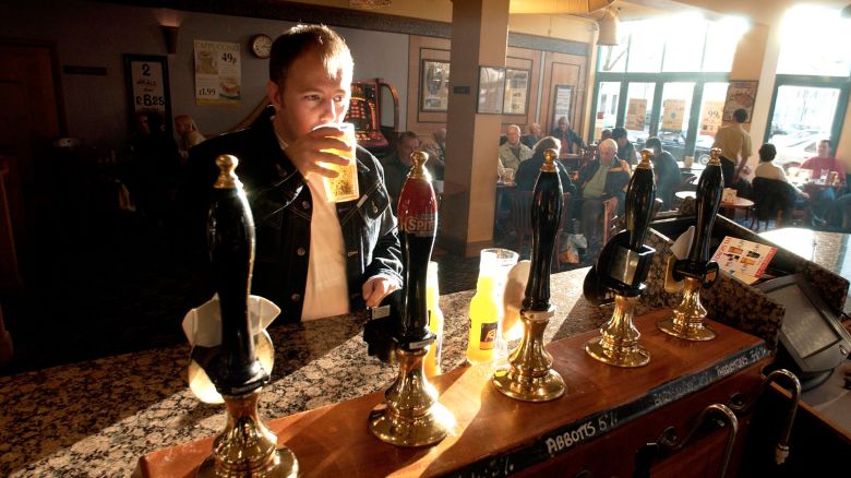 A9GCBD A man sinking a quiet pint in a traditional English pub on a sunny afternoon
