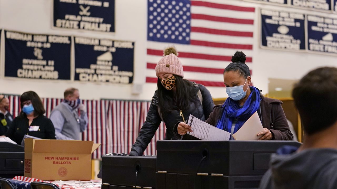 Two women, wearing protective masks due to the Covid-19 virus outbreak, cast their ballots at a polling station at Windham, New Hampshire High School on Tuesday.