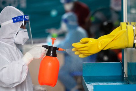 An employee of the Mugda Medical College and Hospital sprays disinfectant on gloves after a nasal swab Covid-19 test was administered in Dhaka on June 17.