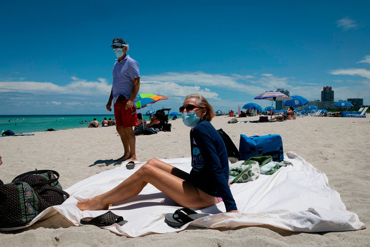 A woman sunbathes at the beach next to her husband, both wearing face masks, in Miami Beach, Florida on June 16.