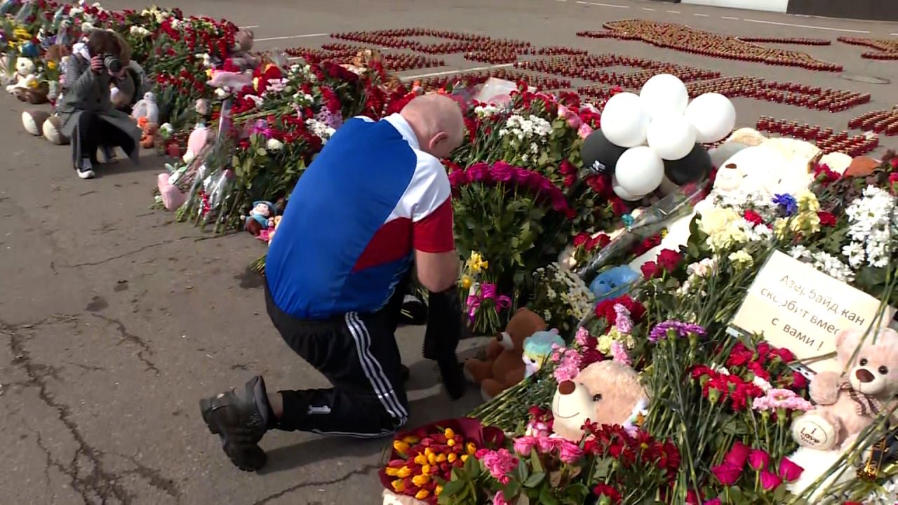 A mans lays flowers at a makeshift memorial outside Crocus City hall on Monday.