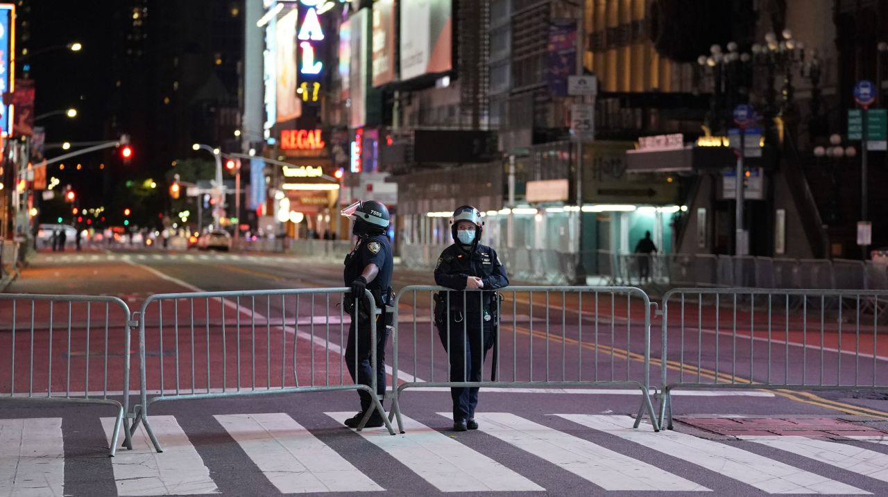 Police officers lean against a barricade in a closed off Times Square shorty before the 11 p.m. curfew went into effect June 1 in New York City.