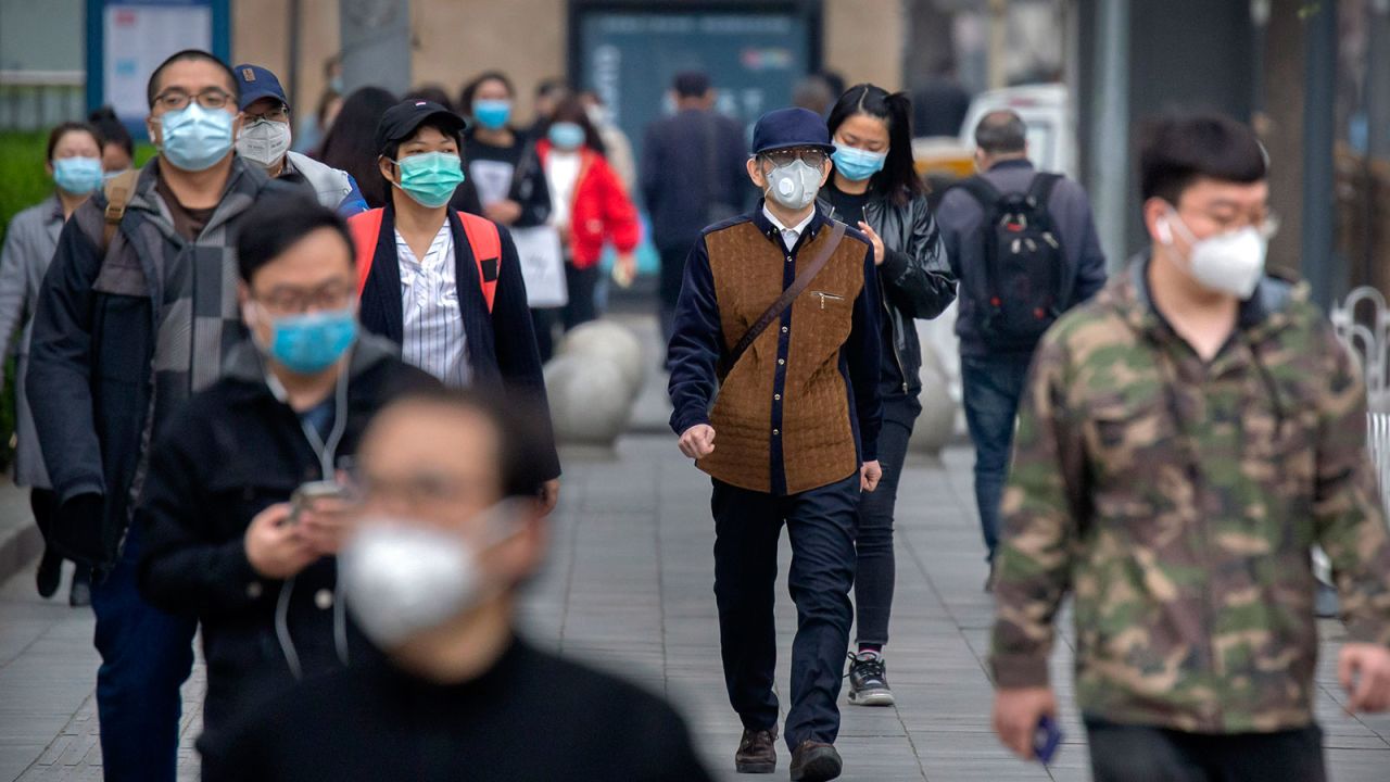 Commuters wear face masks to protect against the spread of new coronavirus as they walk along a street in Beijing on April 9.