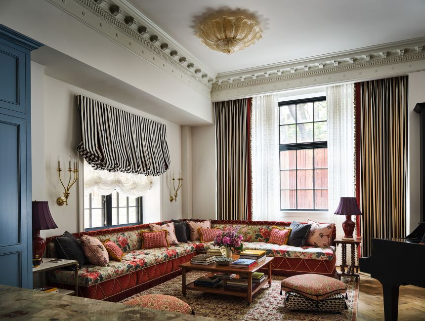 The living room of Deschanel and Scott’s duplex features floral upholstery, striped curtains and a custom rug.