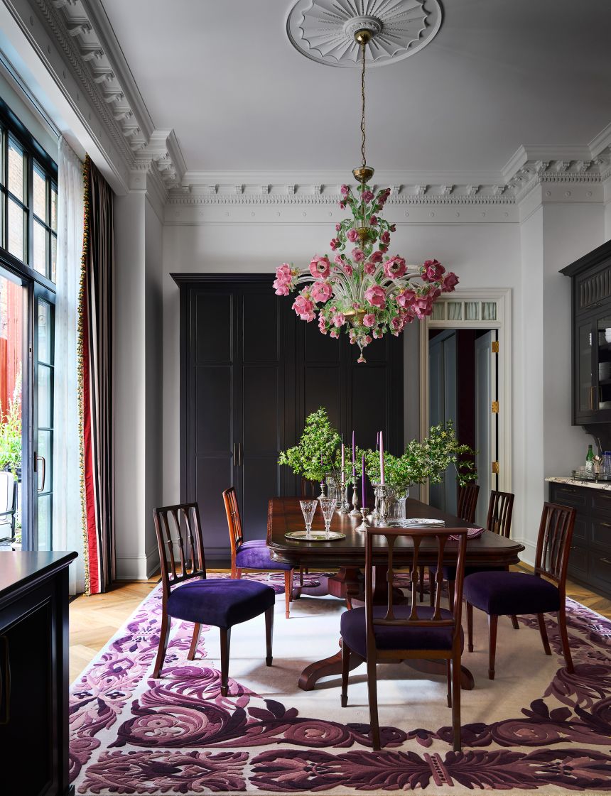 In the dining room, a floral Bottega Veneziana chandelier hangs above a table and antique chairs.