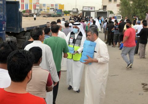 Workers distribute food to residents in the area of Jleeb Al-Shuyoukh, Kuwait, on April 9. 