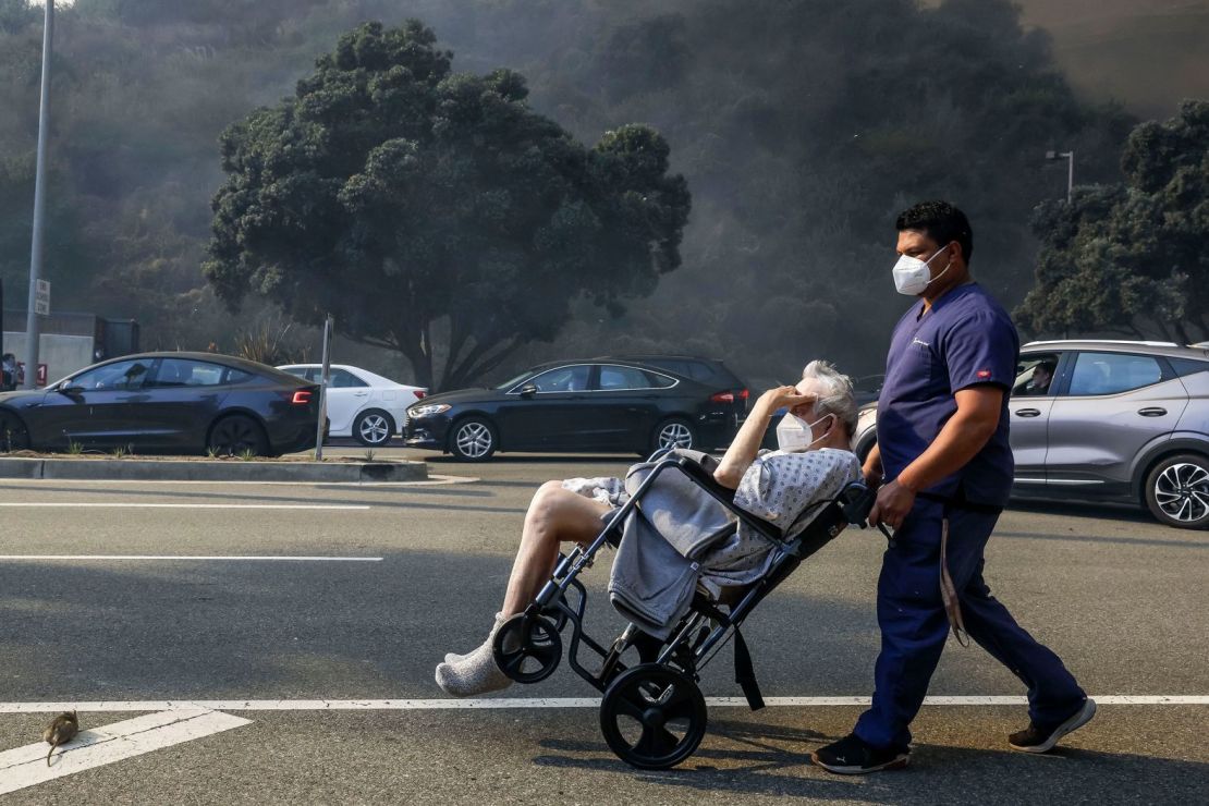 Un hombre en silla de ruedas es evacuado de un barrio amenazado por el fuego el martes.