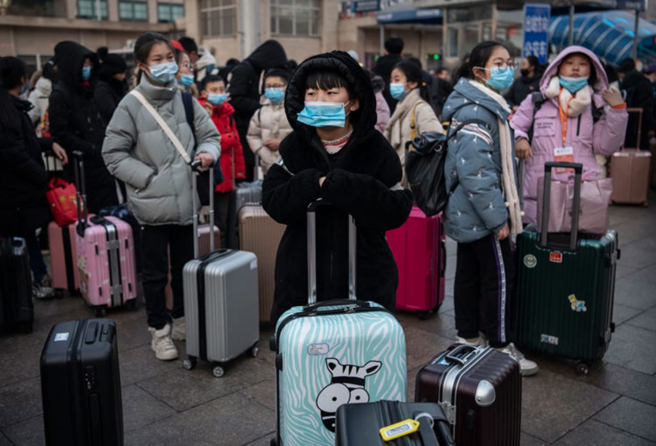 Chinese children wear protective masks as they wait to board trains at Beijing Railway station before the annual Spring Festival.