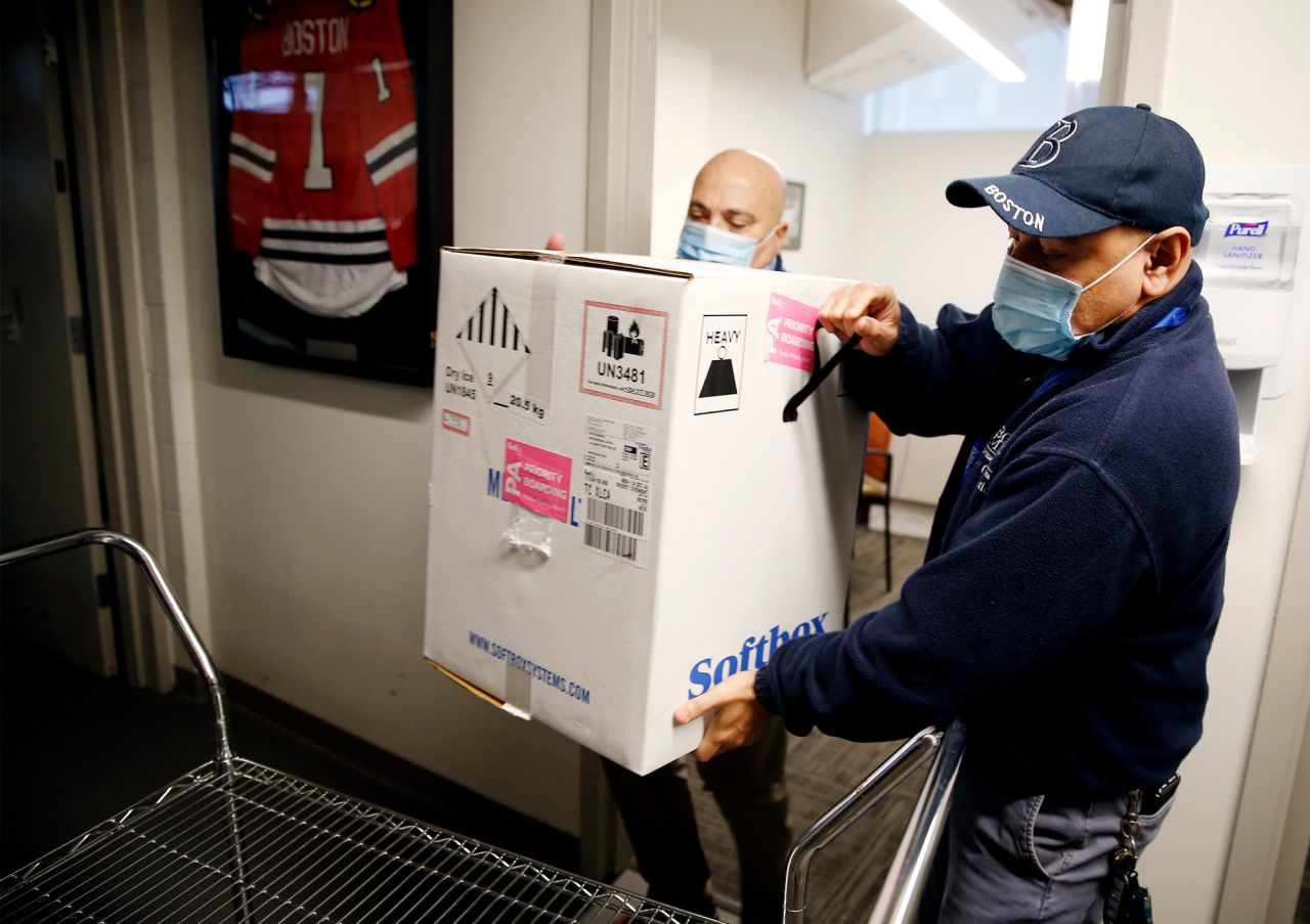 Victor Ruiz with Boston Medical Center Supply Chain Operations and Richard Guarino, left, BMC Supply Chain Operations Associate Director place the hospital's first shipment of the Pfizer-BioNTech COVID-19 vaccine on a cart to deliver to the pharmacy at Boston Medical Center on December 14 in Boston. 