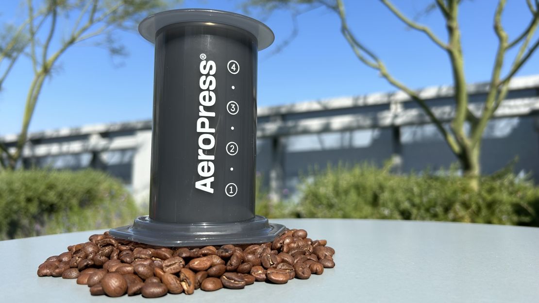 AeroPress coffee maker on a bed of coffee beans