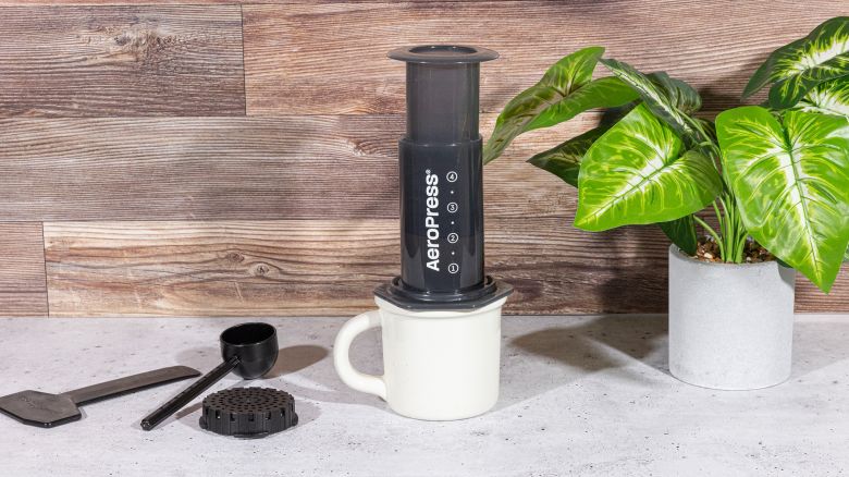 AeroPress coffee maker next to a houseplant