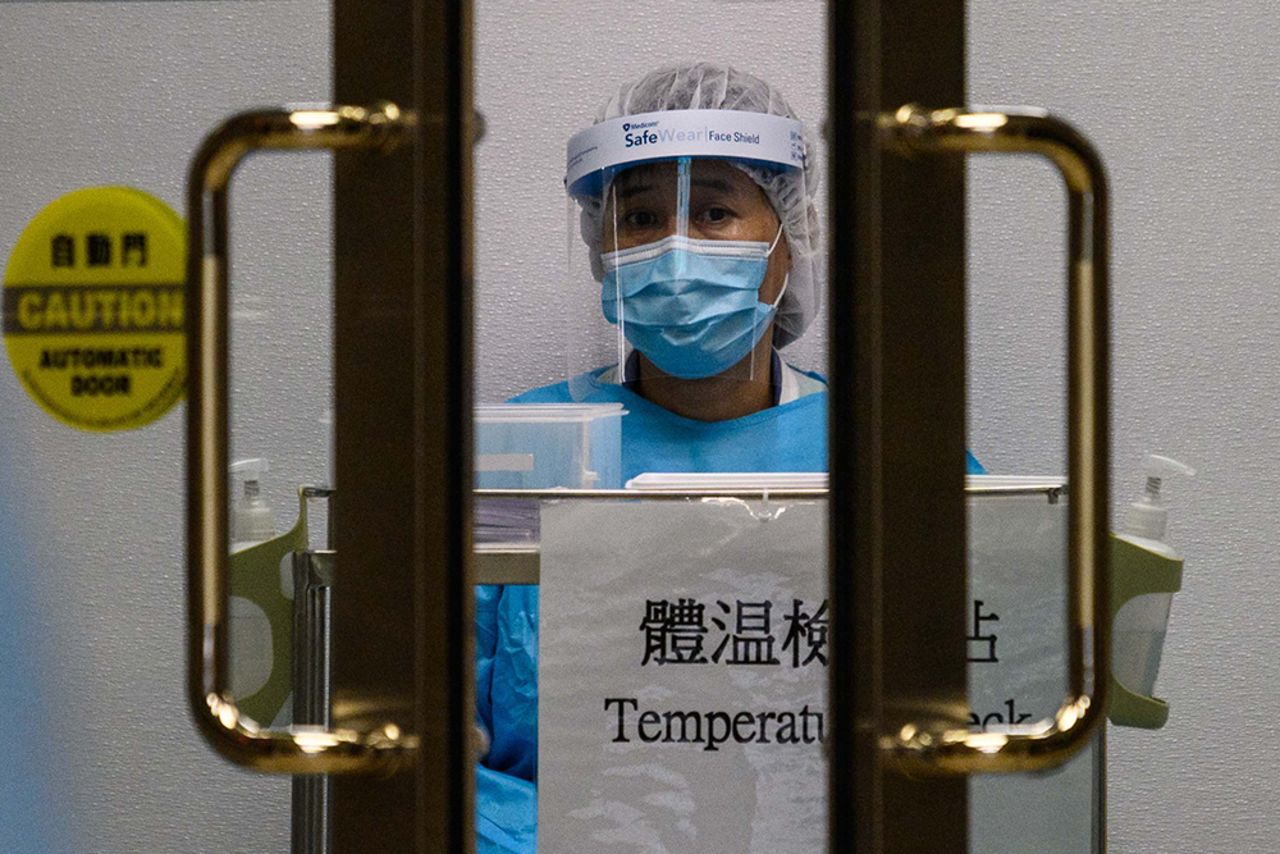 A medical worker wearing protective gear waits to take the temperature of people entering Princess Margaret Hospital in Hong Kong on February 4