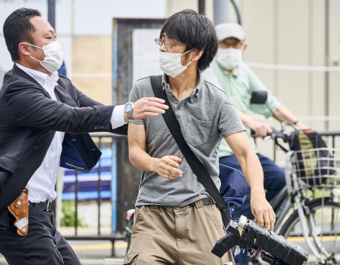 Tetsuya Yamagami, center, throwing a weapon, is detained near the site of gunshots in Nara, western Japan, on July 8.