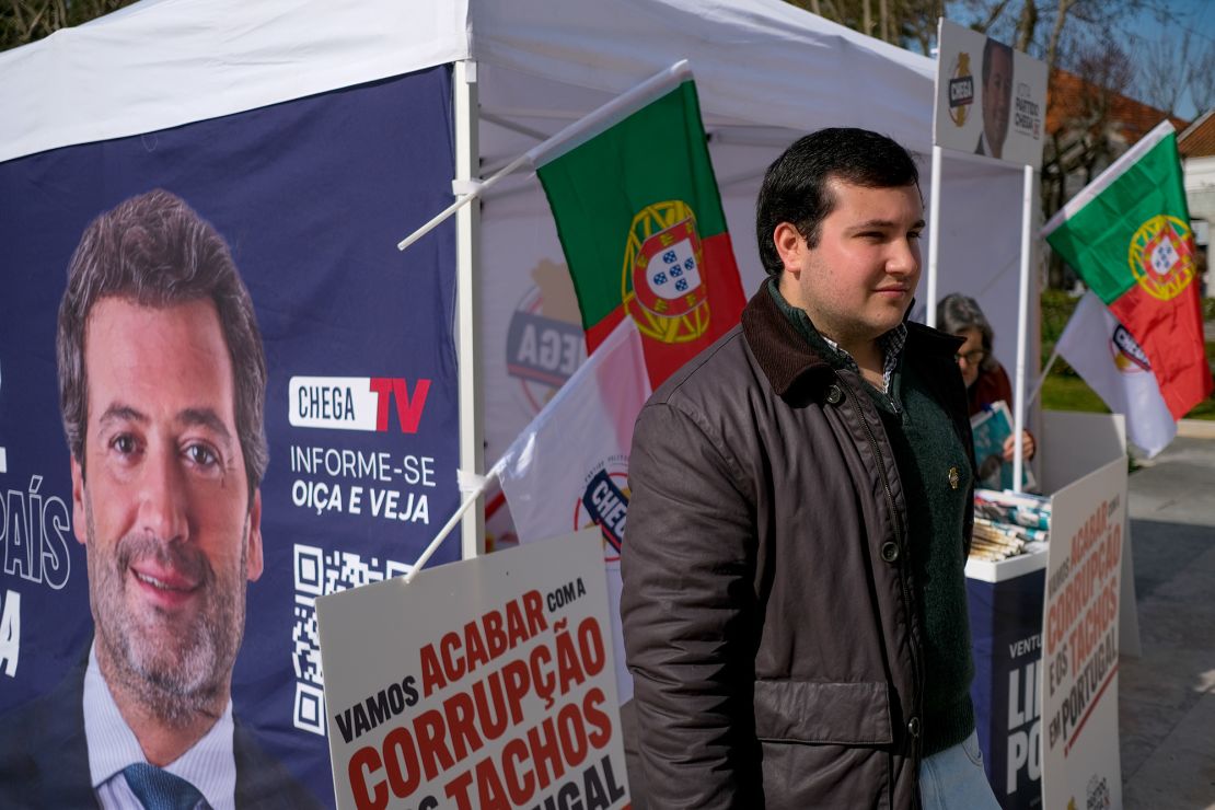 Afonso Mestre, 20, stands next to a Chega party campaign booth.