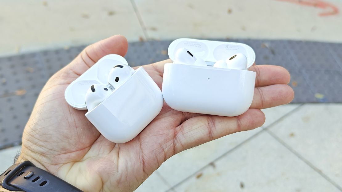 Hand holding both the Airpods 4 and Airpods Pro 2 with cases open.