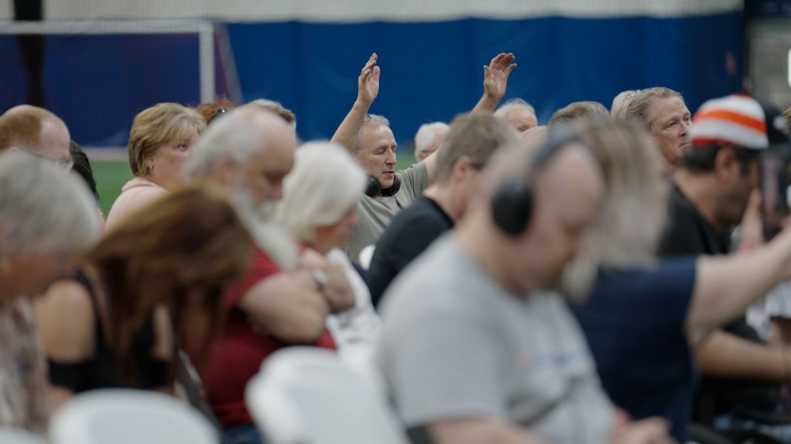 A man raises his hands in prayer at a town hall on Alberta independence in Red Deer.