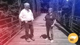 Hot Springs Mayor Abby Norton walks the town’s Old Red Bridge with John King while discussing Helene recovery efforts and challenges.