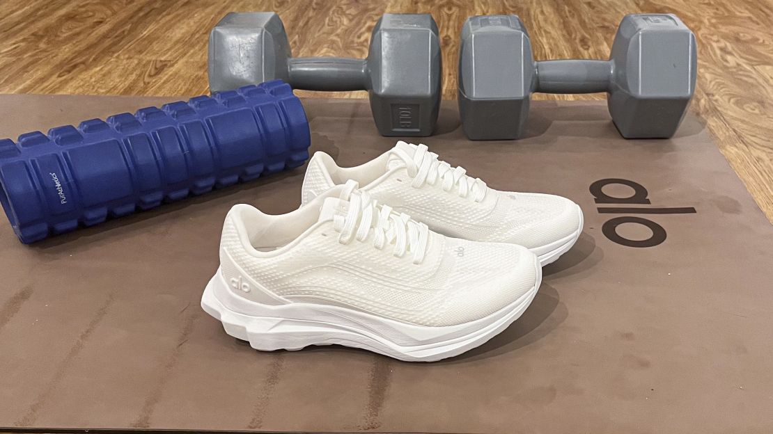 White Alo Runners on a yoga mat next to weights.