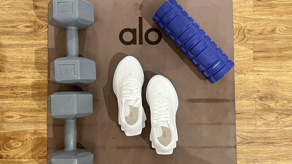 White Alo Runners on a yoga mat next to weights.