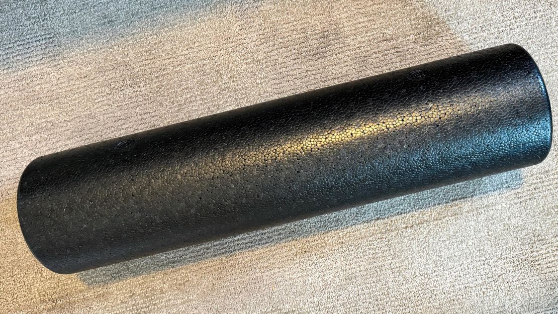 An Amazon Basics High-Density Round Foam Roller on a carpet surface.