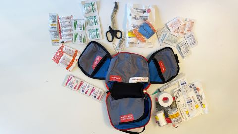 The Adventure Medical Kits Mountain Series Backpacker first aid kit, with all contents laid out on a white tabletop