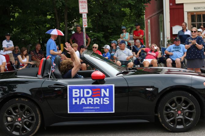 A Biden/Harris campaign sign is displayed on a car during the parade.