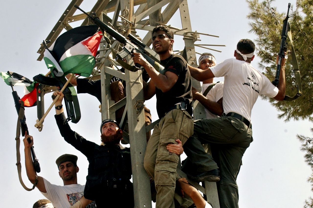 Zakaria al-Zubeidi, a local leader of the Al-Aqsa Martyrs Brigades, center, and other members of his group hold their weapons and Palestinian flags as they celebrate the Israeli withdrawl in the West Bank town of Jenin, on September 21, 2005.