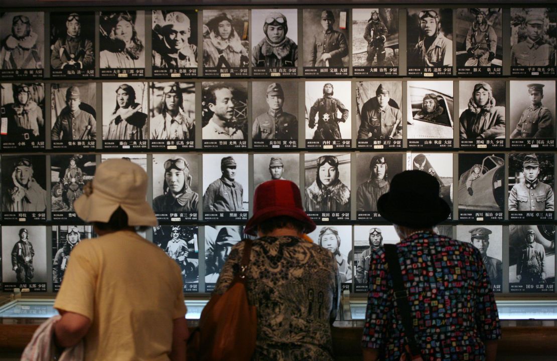 Three women look at photos of Japanese kamikaze pilots, who gave their lives in WWII suicide attacks against US forces, hanging on a wall at the Chiran Peace Museum.