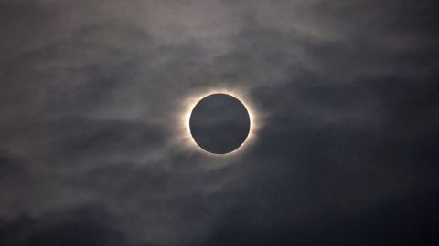 A total solar eclipse is visible through the clouds as seen from Vagar on the Faeroe Islands, Friday, March 20, 2015.  Apart from a few small breaks, a blanket of clouds in the Faeroe Islands blocked thousands of people there from experiencing the full effect of the total eclipse.  (AP Photo/Eric Adams)