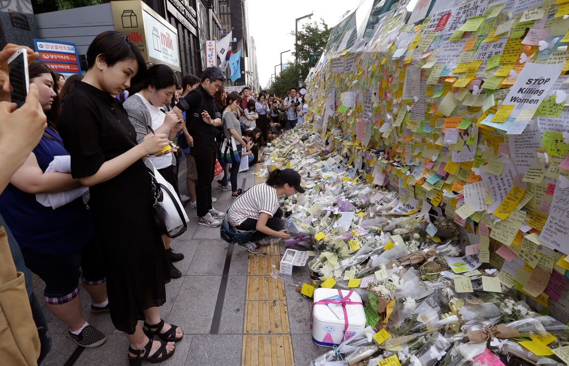 A woman places a flower for a South Korean woman who was stabbed to death at an exit of Gangham subway station in Seoul on May 21, 2016.