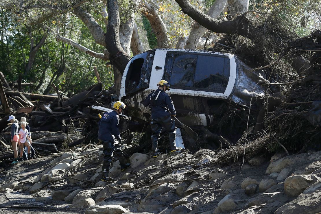 Members of the Los Angeles County Fire Department Search and Rescue crew work on a car trapped under debris from a mudslide in Montecito, California, on January 10, 2018.