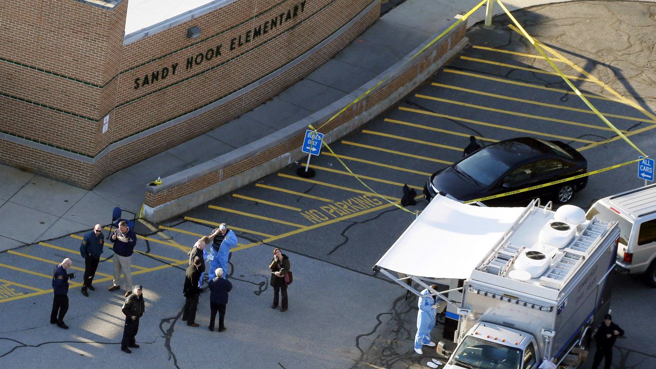 In this Dec. 14, 2012, file photo, officials stand outside of Sandy Hook Elementary School after a shooting in Newtown, Connecticut.