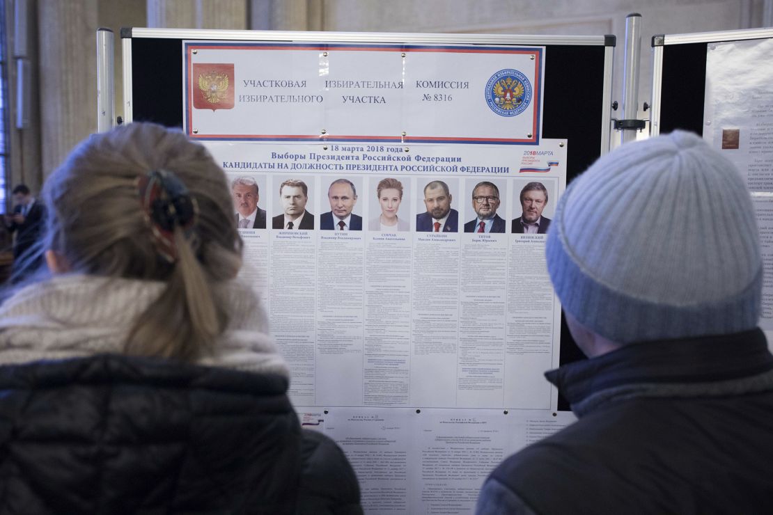 Russian citizens at the Russian embassy in Berlin, Germany, look at a list of candidates in the 2018 Russian presidential election.