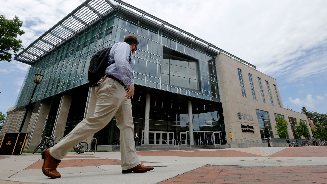 In this June 20, 2019, photo a Virginia Commonwealth University student walks past the library at the school in Richmond, Va.
