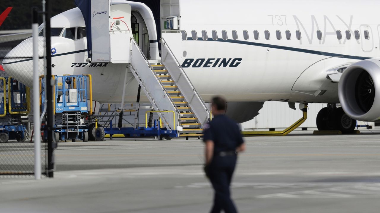 In this March 14, 2019, file photo, a worker walks next to a Boeing 737 MAX 8 airplane parked at Boeing Field in Seattle. Boeing said Thursday, July 18, it will take a $4.9 billion charge to cover possible compensation to airlines whose Max jets remain grounded after two deadly accidents.