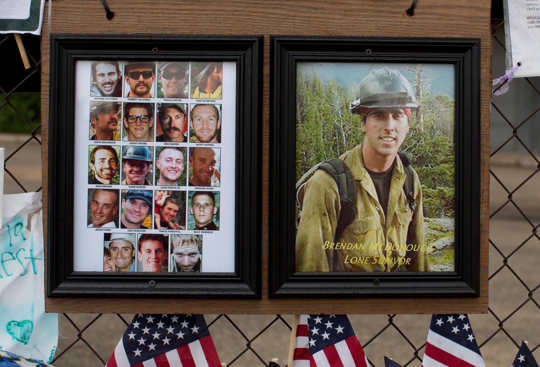 Photos of the 19 fallen Granite Mountain Hotshot firefighters, alongside survivor Brendan McDonough, hang on a fence outside Fire Station No. 7 in Prescott, Arizona, on July 5, 2013.