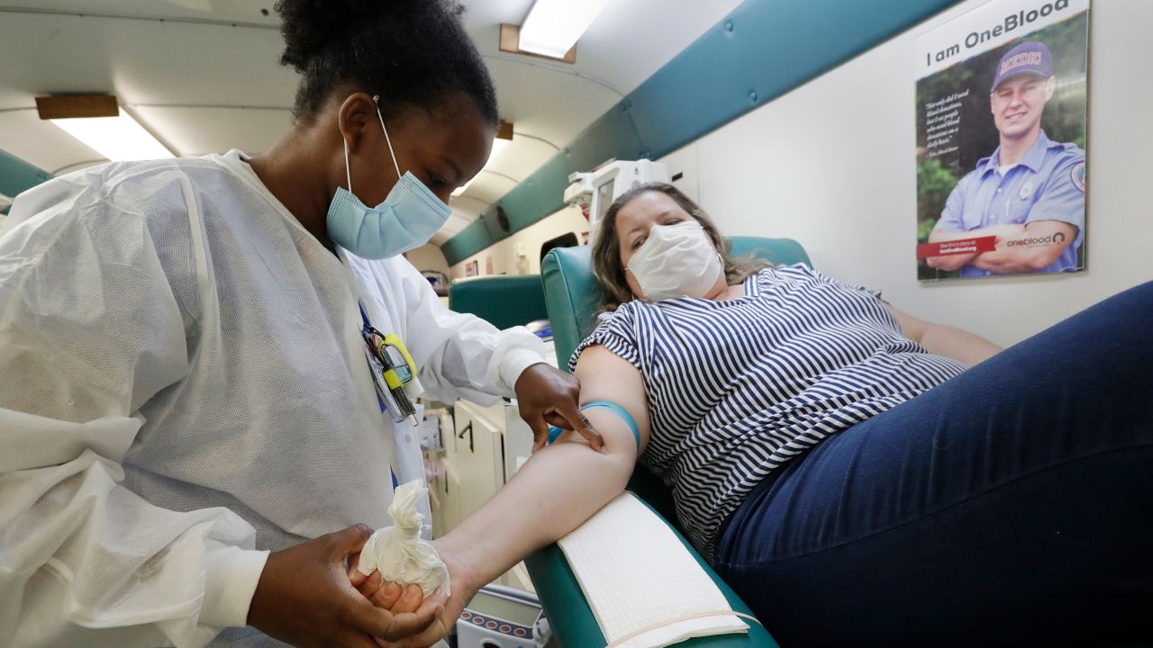 Phlebotomist Josianne Fiefie, left, looks for a vein as Maria Teresa Andreychuk prepares to donate blood aboard a OneBlood blood donation bus, Wednesday, April 22, 2020, in Miami.