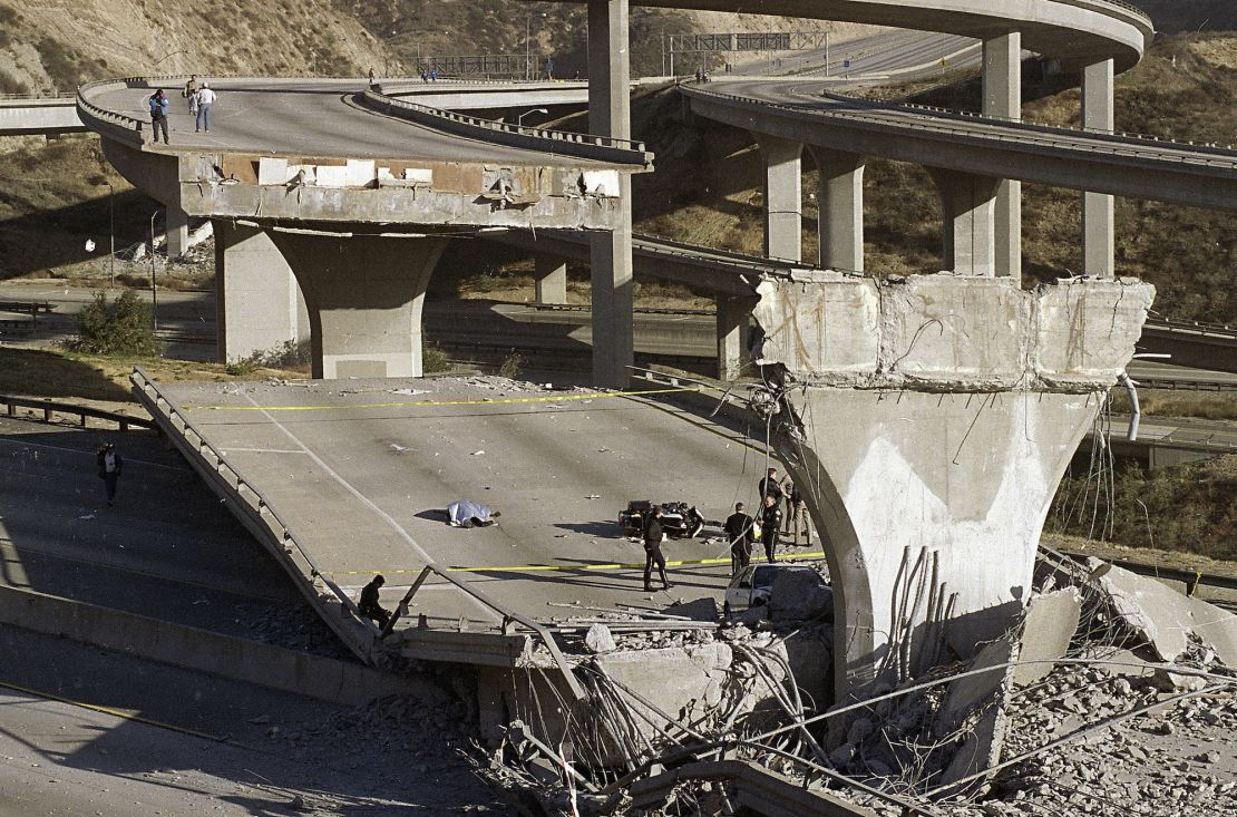 The covered body of Los Angeles Police Officer Clarence Wayne Dean lies near his motorcycle which plunged off the State Highway 14 overpass that collapsed onto Interstate 5 during the Northridge earthquake.