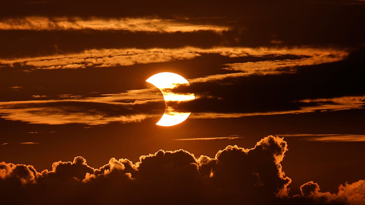 A partial solar eclipse rises behind clouds on June 10, 2021, in Arbutus, Maryland.