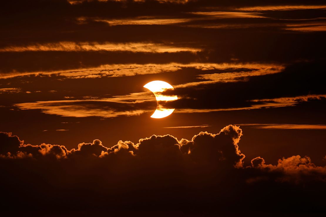 High-level clouds are seen at the top of the image as a partial solar eclipse unfolds behind clouds, Thursday, June 10, 2021, in Arbutus, Maryland.