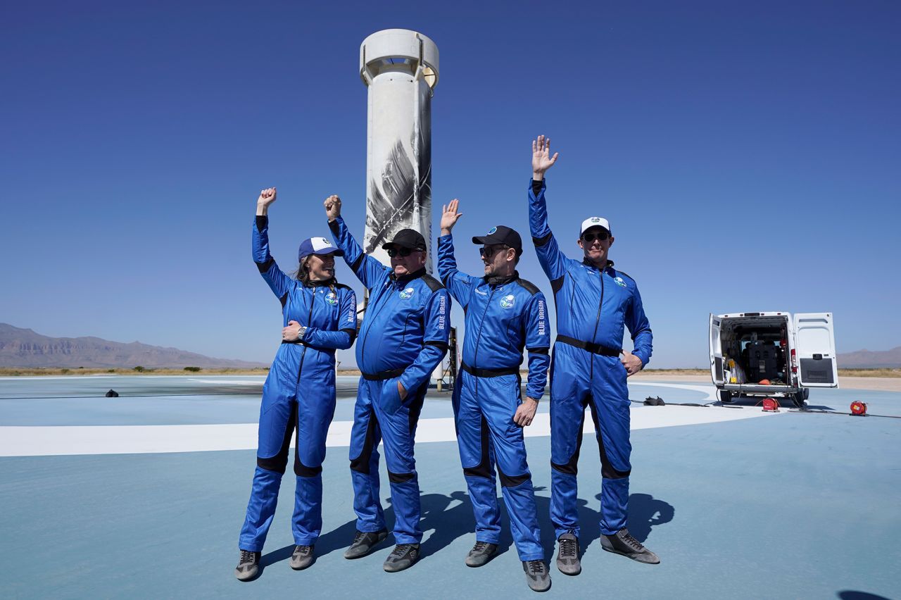 Blue Origin New Shepard passengers (from left) Audrey Powers, William Shatner, Chris Boshuizen and the late Glen de Vries raise their hands in front of the rocket booster that carried them into space near Van Horn, Texas, in October 2021.